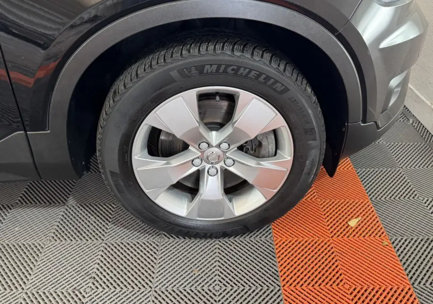 Gros plan sur la roue avant gauche noire du Volvo XC40 Recharge T5 avec jante argentée et pneu Michelin.