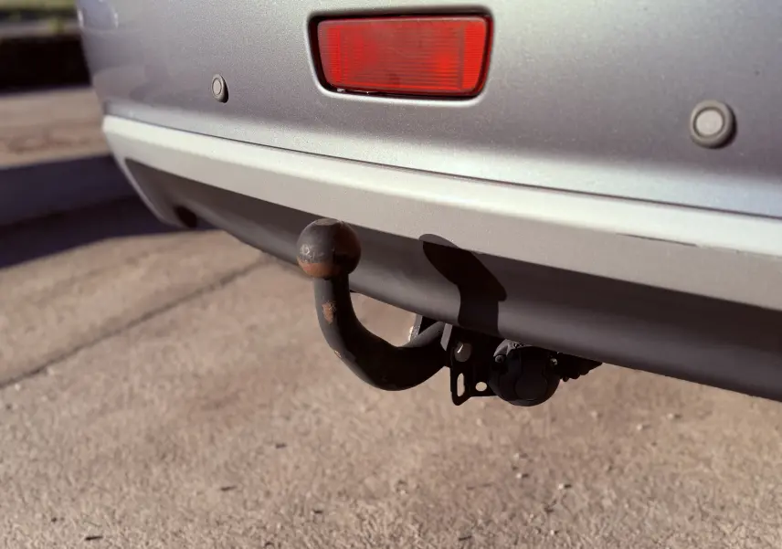 Gros plan sur l'attelage arrière rouillé d'un Mitsubishi ASX gris, avec feu rouge et capteurs de recul visibles.