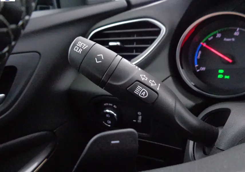 Gros plan sur la commande de clignotants et régulateur de vitesse dans l'habitacle noir de l'Opel Grandland X hybride.