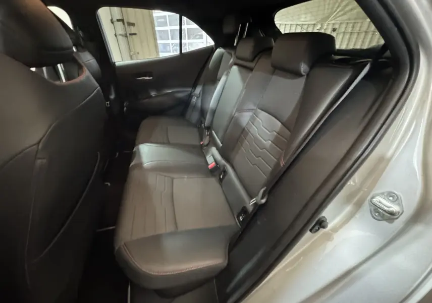 Vue intérieure côté droit des sièges arrière en cuir noir avec surpiqûres rouges d'une Toyota Corolla Hybride 2021 gris clair.