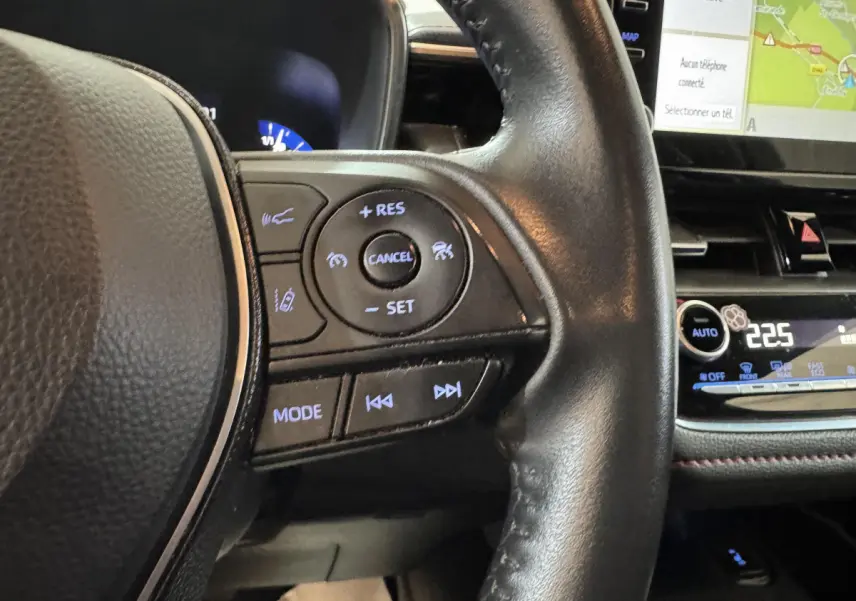 Gros plan sur le volant cuir noir de la Toyota Corolla Hybride 122h 2021, avec commandes multifonctions et écran tactile visible.