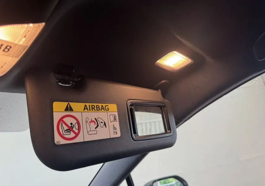 Vue intérieure côté conducteur du pare-soleil avec miroir et avertissement airbag dans une Toyota Corolla hybride gris clair 2021.