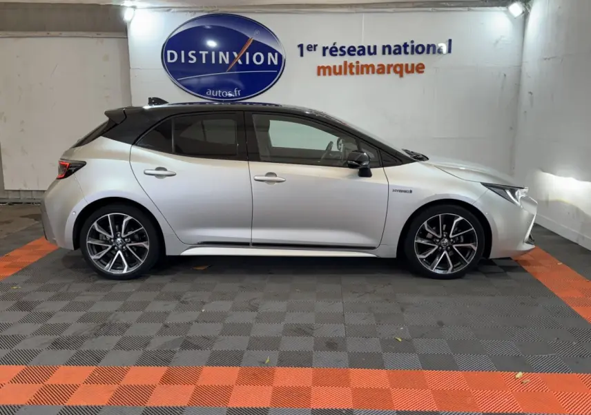 Profil droit d'une Toyota Corolla Hybride gris clair 2021, avec toit noir et jantes alliage distinctives.