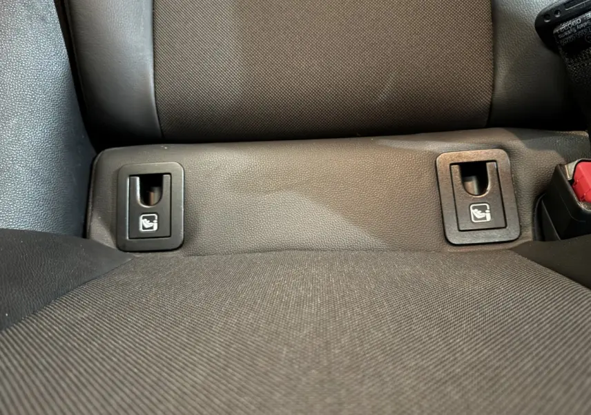 Gros plan sur les fixations Isofix noires intégrées à la banquette arrière grise de la Toyota Corolla Hybride 122h Collection.