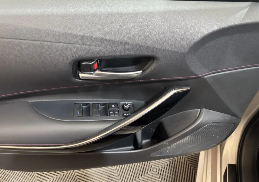 Gros plan sur la porte intérieure côté conducteur de la Toyota Corolla Hybride 122h Collection gris clair, avec commandes électriques.