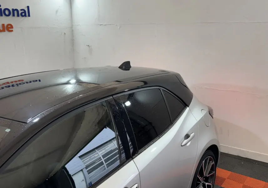 Vue 3/4 arrière droite d'une Toyota Corolla Hybride 122h Collection gris clair avec toit noir et vitres teintées.