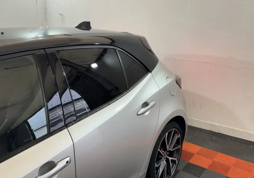 Vue arrière côté droit d'une Toyota Corolla Hybride 122h Collection gris clair avec toit noir et jantes alliage.