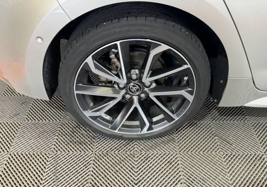 Gros plan sur la roue arrière droite gris clair d'une Toyota Corolla Hybride 122h Collection avec jante alliage noire et argent.