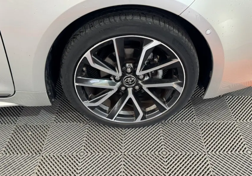 Gros plan sur la roue avant droite de la Toyota Corolla Hybride gris clair, jante alliage au design moderne.