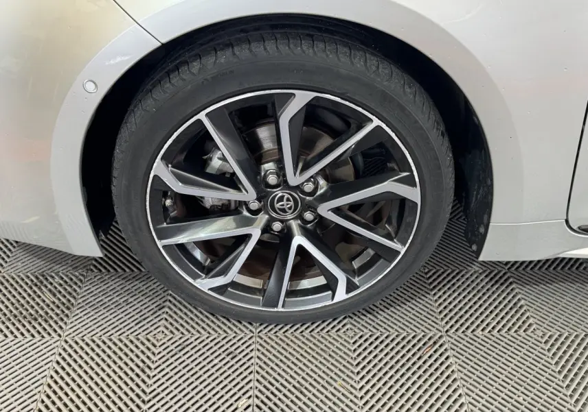 Gros plan sur la roue avant droite gris clair de la Toyota Corolla Hybride 122h Collection avec jante alliage noire et argent.