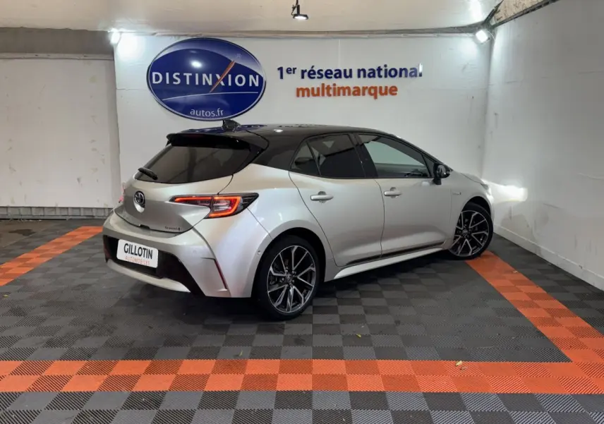 Vue 3/4 arrière droite d'une Toyota Corolla Hybride 122h Collection gris clair avec toit noir et jantes alliage.
