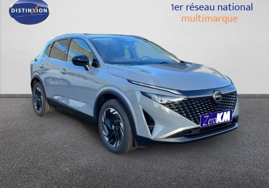 Vue 3/4 avant du Nissan Qashqai 2025 gris argile métal avec calandre noire et jantes au design moderne.