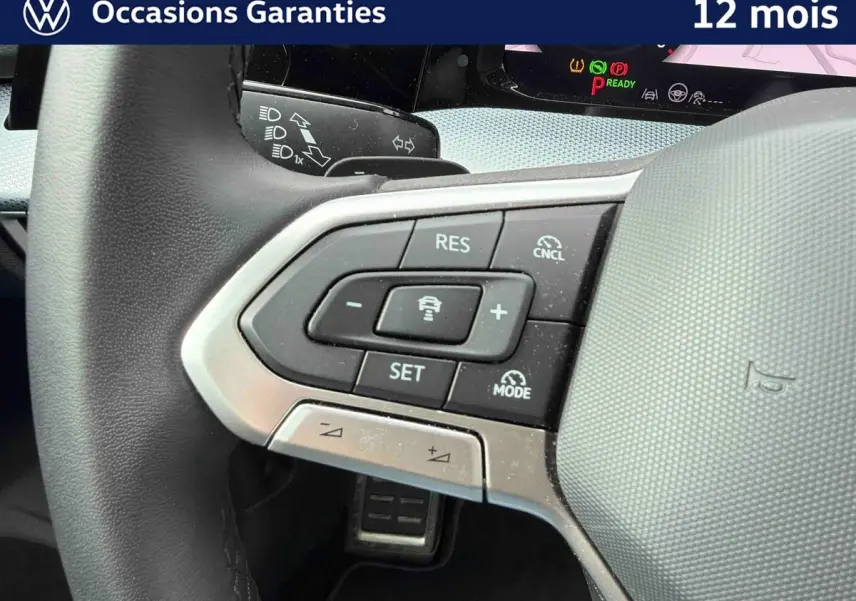 Gros plan sur le volant côté gauche de la Volkswagen Golf 2025, montrant les commandes du régulateur de vitesse et d'assistance.