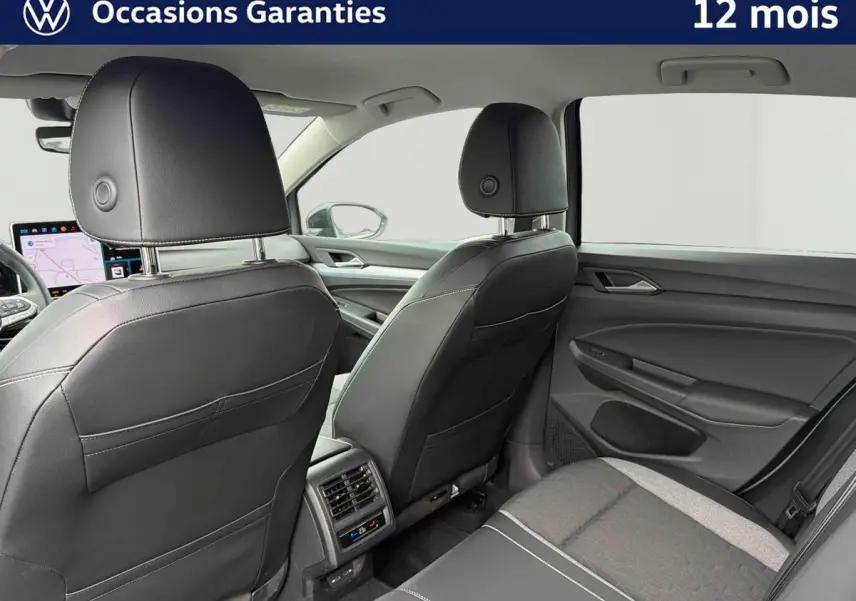 Vue intérieure arrière droite de la Volkswagen Golf gris, montrant les sièges en cuir noir et la console avec aérateurs et commandes climatiques.