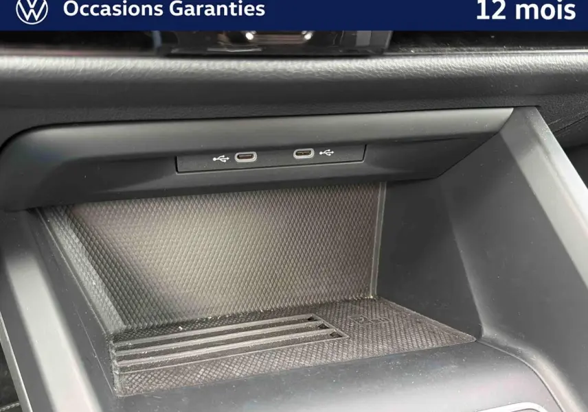 Gros plan sur la console centrale d'une Volkswagen Golf grise, montrant deux ports USB-C et un espace de rangement.