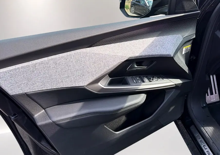 Intérieur côté conducteur du Peugeot 5008 Hybrid 145 GT e-dcs6 2025, porte ouverte avec habillage tissu gris et cuir noir.
