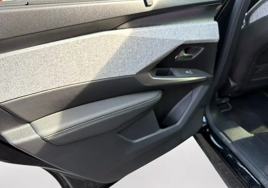 Vue rapprochée de la porte arrière droite noire du Peugeot 5008 Hybrid 145 GT avec habillage tissu gris et cuir noir.