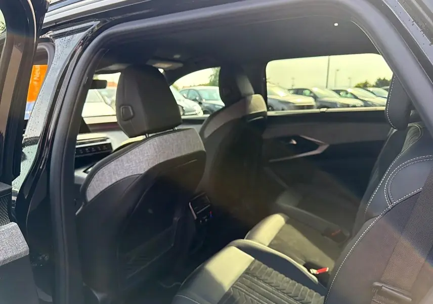 Vue intérieure côté droit du Peugeot 5008 Hybrid 145 GT 2025 noir, montrant les sièges arrière et la finition tissu/cuir.