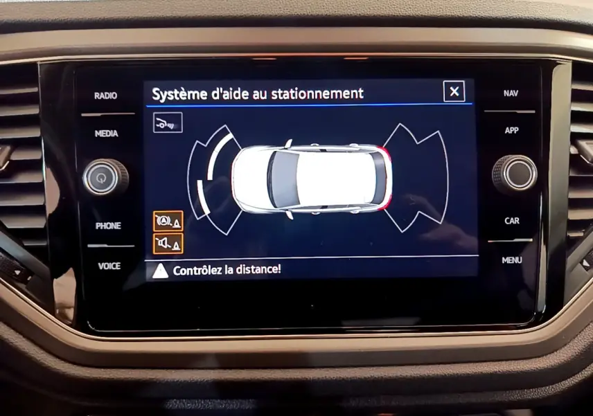Écran tactile du système d'aide au stationnement montrant une vue aérienne du Volkswagen T-Roc gris foncé.