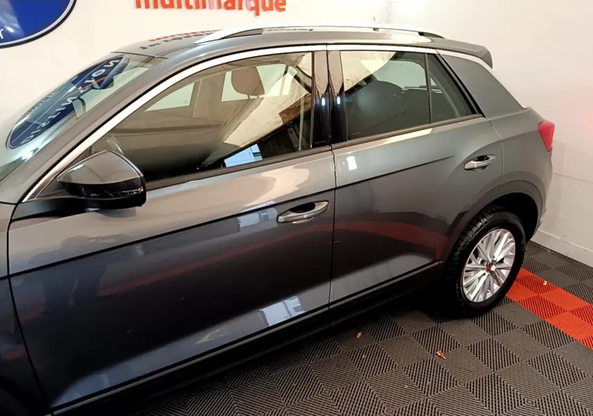 Vue latérale droite du Volkswagen T-Roc gris foncé, mettant en valeur les lignes épurées et les rétroviseurs noirs.