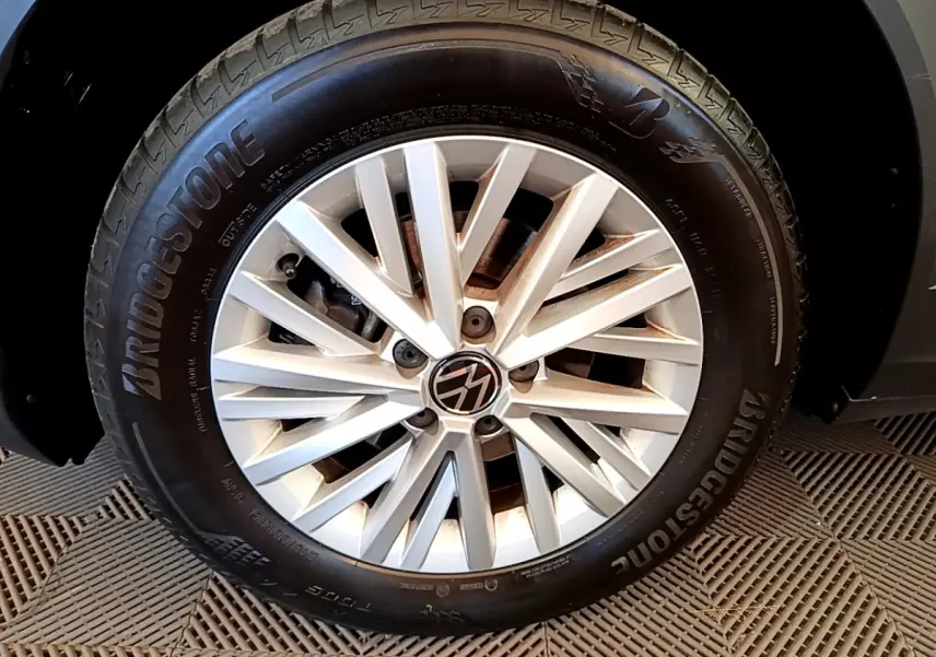 Gros plan sur la roue avant droite du Volkswagen T-Roc gris foncé, avec jante alliage et pneu Bridgestone visible.