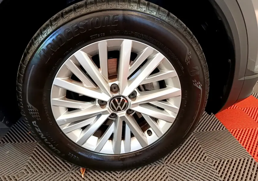 Gros plan sur la roue avant droite du Volkswagen T-Roc gris foncé, mettant en valeur la jante alliage et le pneu Bridgestone.