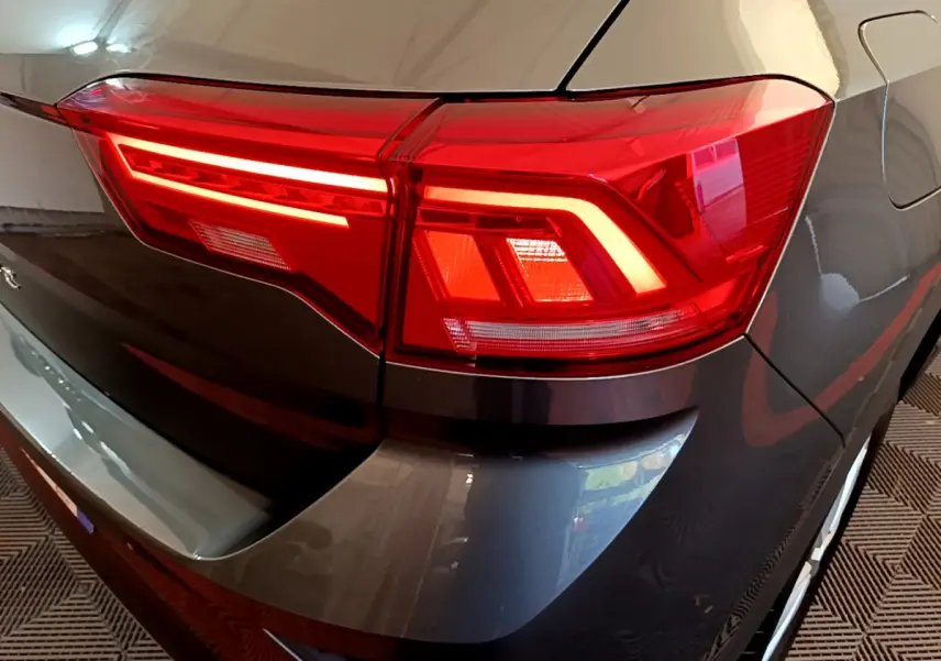 Gros plan sur le feu arrière droit d’un Volkswagen T-Roc gris foncé 2021, soulignant les lignes LED distinctives.