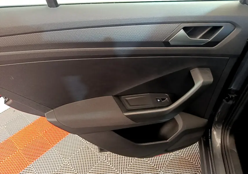 Vue rapprochée de la porte intérieure côté droit du Volkswagen T-Roc gris foncé, avec poignée et commande de vitre.