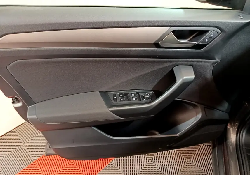 Vue intérieure côté gauche de la porte avant d’un Volkswagen T-Roc gris foncé avec commandes de vitres et serrure.