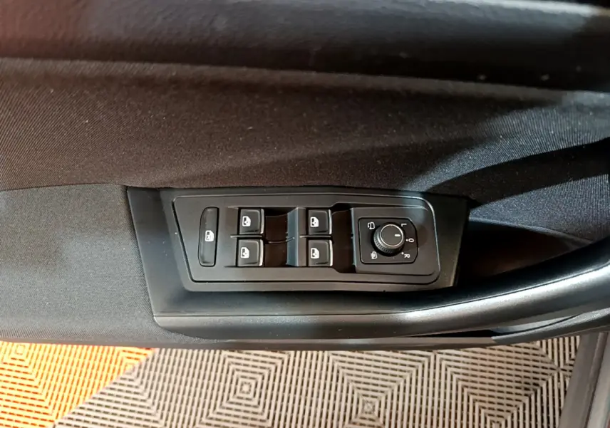 Vue rapprochée des commandes de lève-vitres et rétroviseurs sur la porte côté conducteur d'un Volkswagen T-Roc gris foncé.