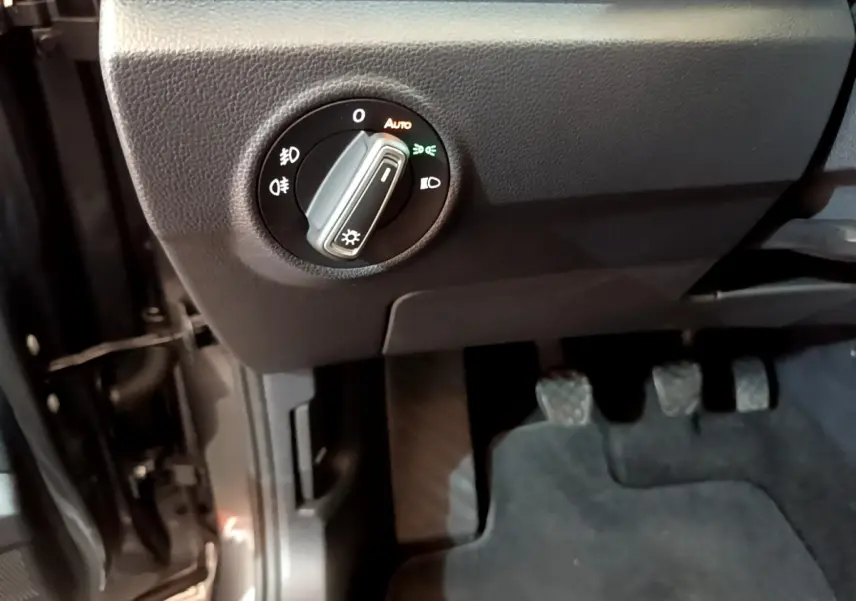 Détail intérieur côté gauche du Volkswagen T-Roc 2021, bouton de commande des phares et pédales visibles.