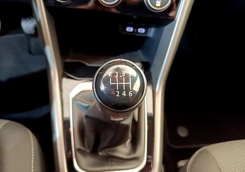 Gros plan sur le levier de vitesse manuel noir du Volkswagen T-Roc 1.0 TSI 110 Lounge Business, intérieur gris.