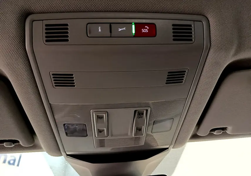 Vue intérieure du plafonnier gris clair du Volkswagen T-Roc 1.0 TSI 110 Lounge Business avec boutons de commande et alerte SOS allumée.
