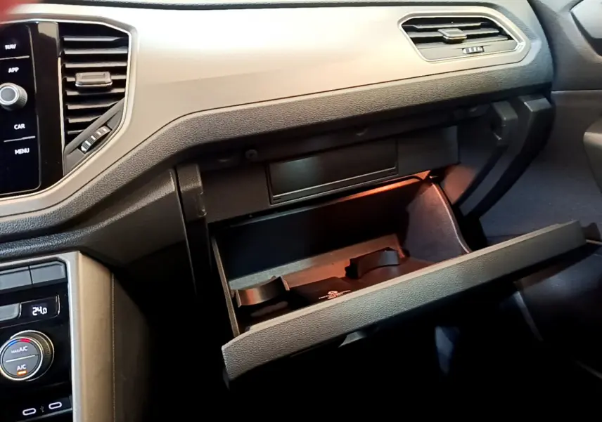 Intérieur du Volkswagen T-Roc 1.0 TSI 110 Lounge Business 2021, vue sur la boîte à gants ouverte et la console centrale gris foncé.