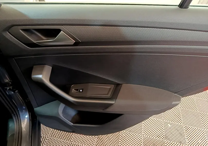 Vue rapprochée de la porte avant gauche gris foncé du Volkswagen T-Roc 2021 avec poignée et commande de vitre électrique.