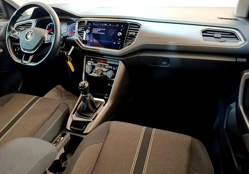 Vue intérieure avant du Volkswagen T-Roc 1.0 TSI 110 Lounge Business, montrant le tableau de bord et la boîte manuelle.