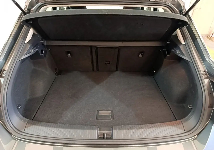 Coffre ouvert vu de l'arrière d'un Volkswagen T-Roc gris foncé, montrant un espace de chargement propre et spacieux.
