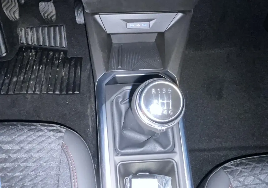 Gros plan sur les commandes au volant gauche de la Renault Clio VI gris Rafale, avec affichage digital en arrière-plan.