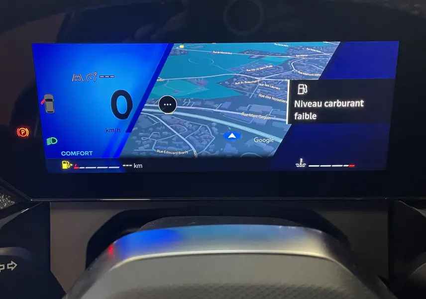 Vue centrée du volant noir perforé de la Renault Clio VI TCe 115ch Techno avec écran numérique et commandes intégrées.