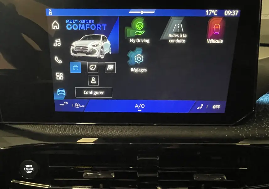 Gros plan sur les commandes de réglage des phares et désactivation du start-stop dans l’habitacle noir d’une Renault Clio VI gris Rafale.