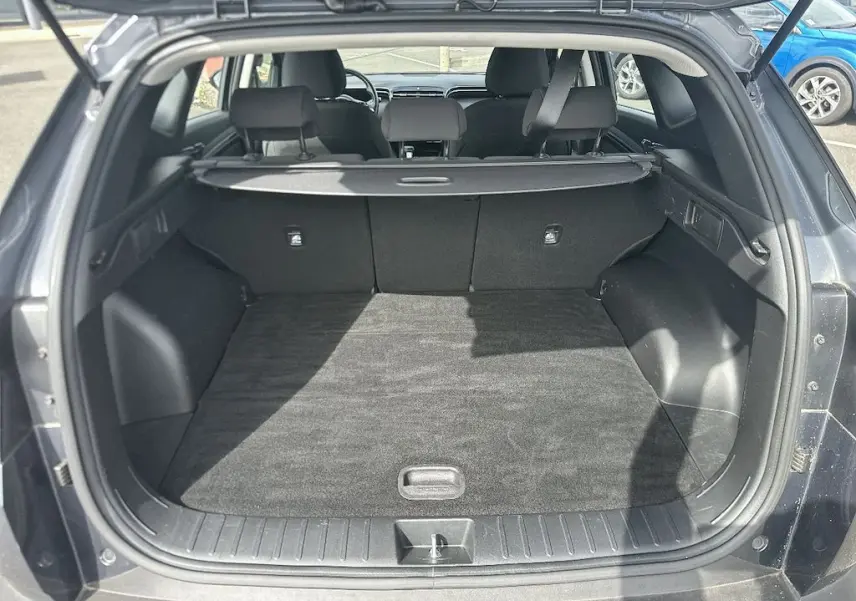 Coffre ouvert vu de l'arrière d'un Hyundai Tucson gris 2023, montrant l'espace de chargement et la plage arrière.