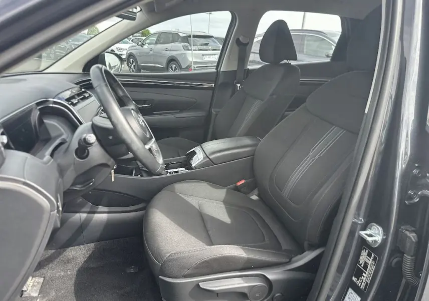Vue intérieure côté conducteur du Hyundai Tucson gris 2023, montrant les sièges avant et le tableau de bord.