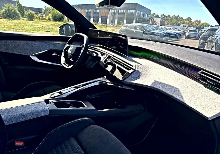 Vue intérieure côté conducteur du Peugeot 5008 Hybrid 145 GT 2025, tableau de bord clair et volant compact noir.