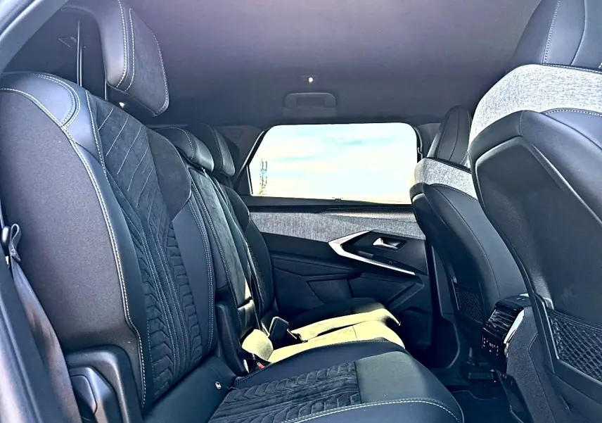 Vue intérieure côté gauche des sièges arrière noirs et gris du Peugeot 5008 Hybrid 145 GT avec appuie-têtes et finitions tissu et cuir.