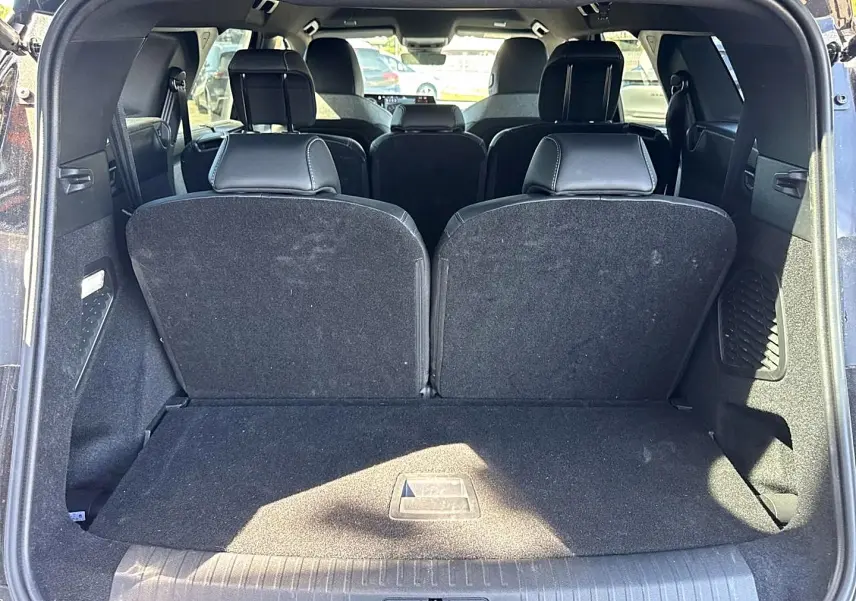 Vue arrière du coffre ouvert du Peugeot 5008 noir, montrant les sièges rang 3 relevés et l'intérieur spacieux.