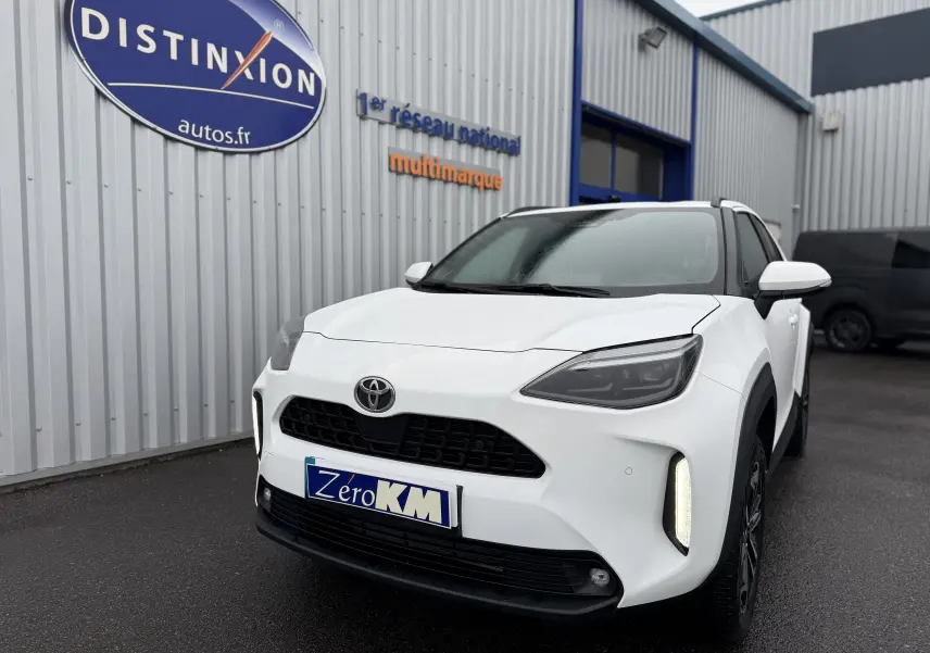 Vue 3/4 avant droite d'une Toyota Yaris Cross blanche pur avec feux LED et calandre noire sur parking extérieur.