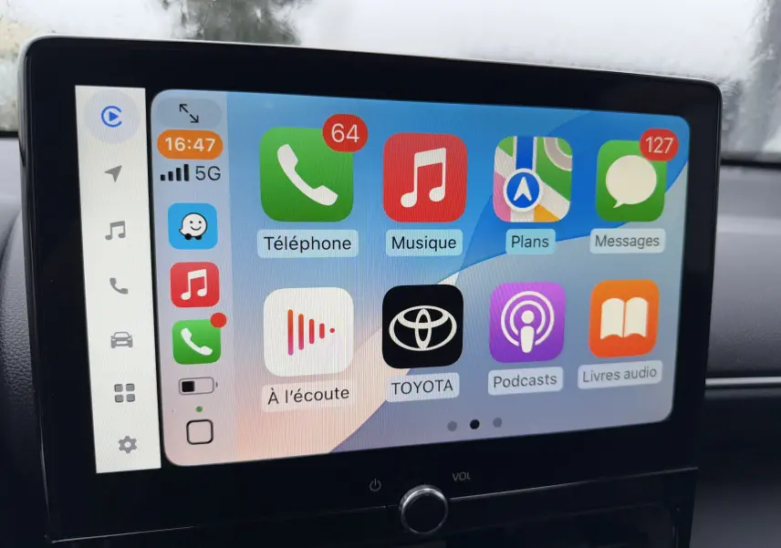 Écran tactile central de la Toyota Yaris Cross blanc pur 2025 affichant les applications Apple CarPlay en intérieur.