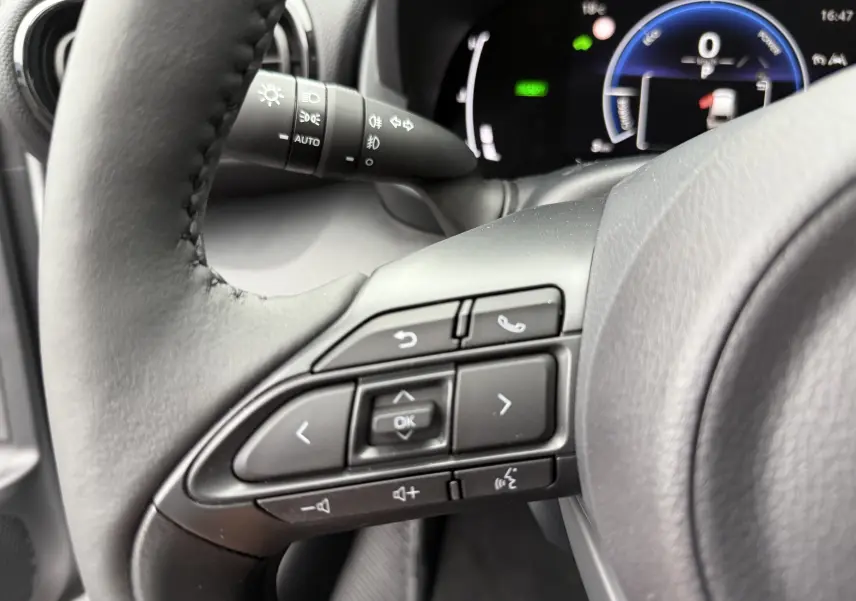 Gros plan sur le volant noir de la Toyota Yaris Cross 2025, montrant les commandes multifonctions et le tableau de bord numérique.