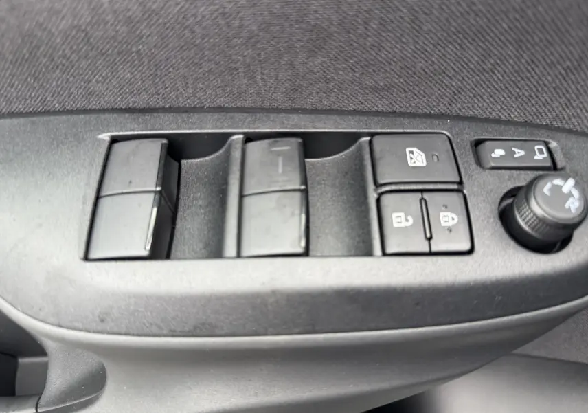 Panneau de commandes des vitres et rétroviseurs côté gauche intérieur d'une Toyota Yaris Cross blanche hybride 2025.