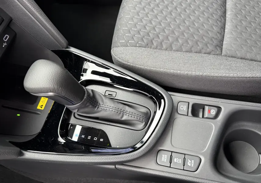 Gros plan sur la console centrale de la Toyota Yaris Cross blanche, montrant le levier de vitesse automatique et les boutons de modes de conduite.